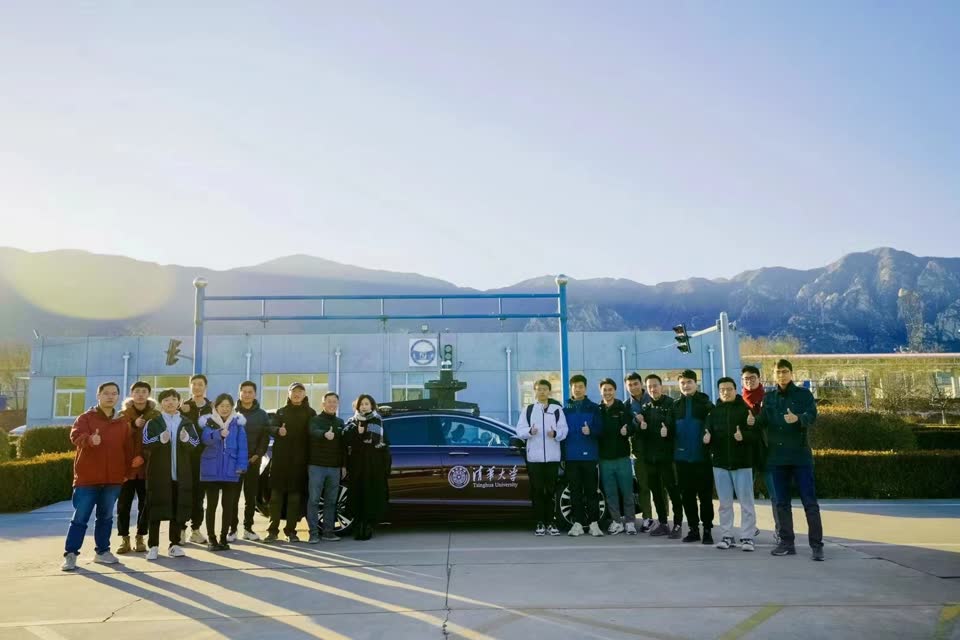 Research team beside a Tsinghua University autonomous test car with a roof sensor rig